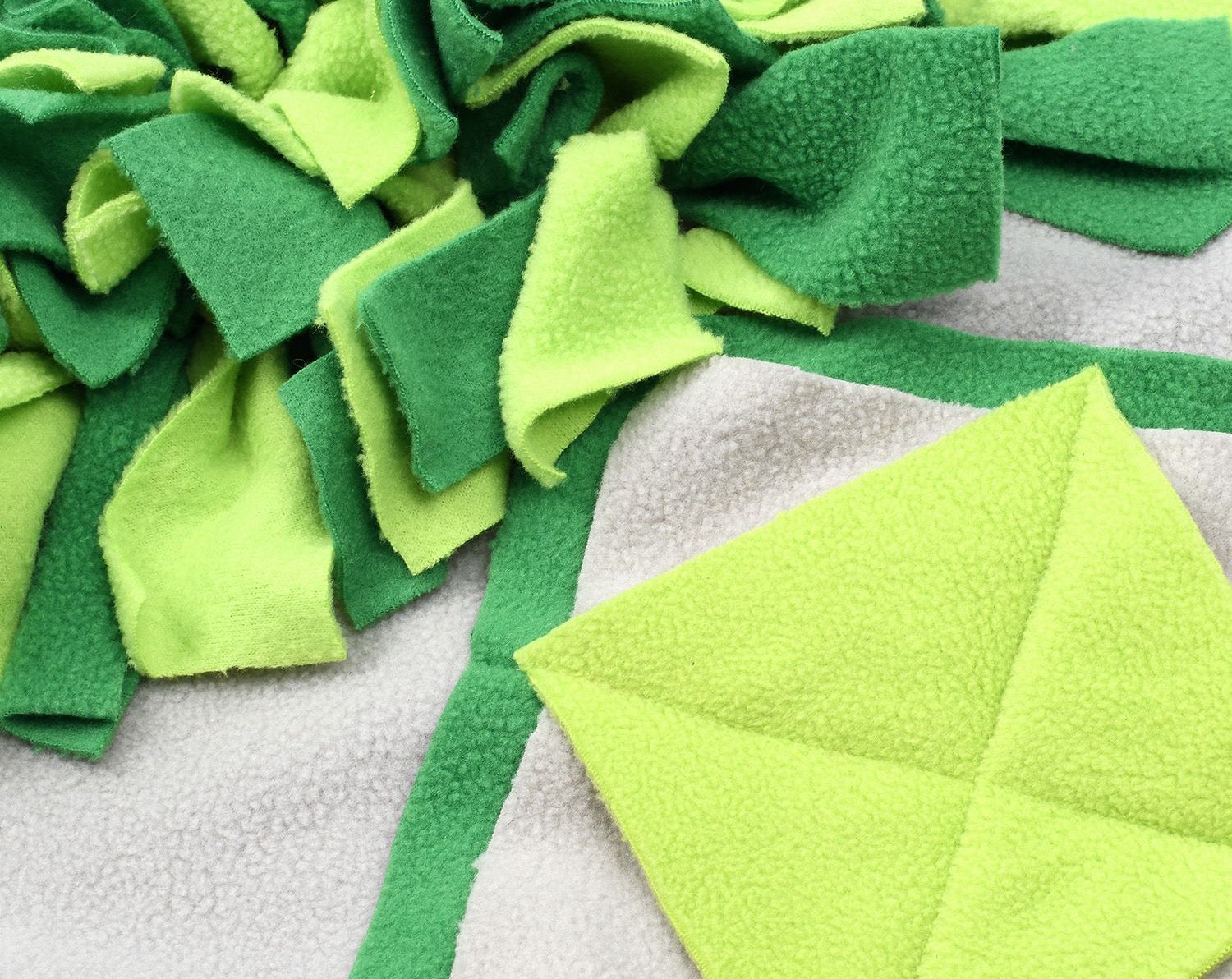 A vibrant green snuffle mat designed for pets, featuring various textures and a rotating top for interactive play and slow feeding.