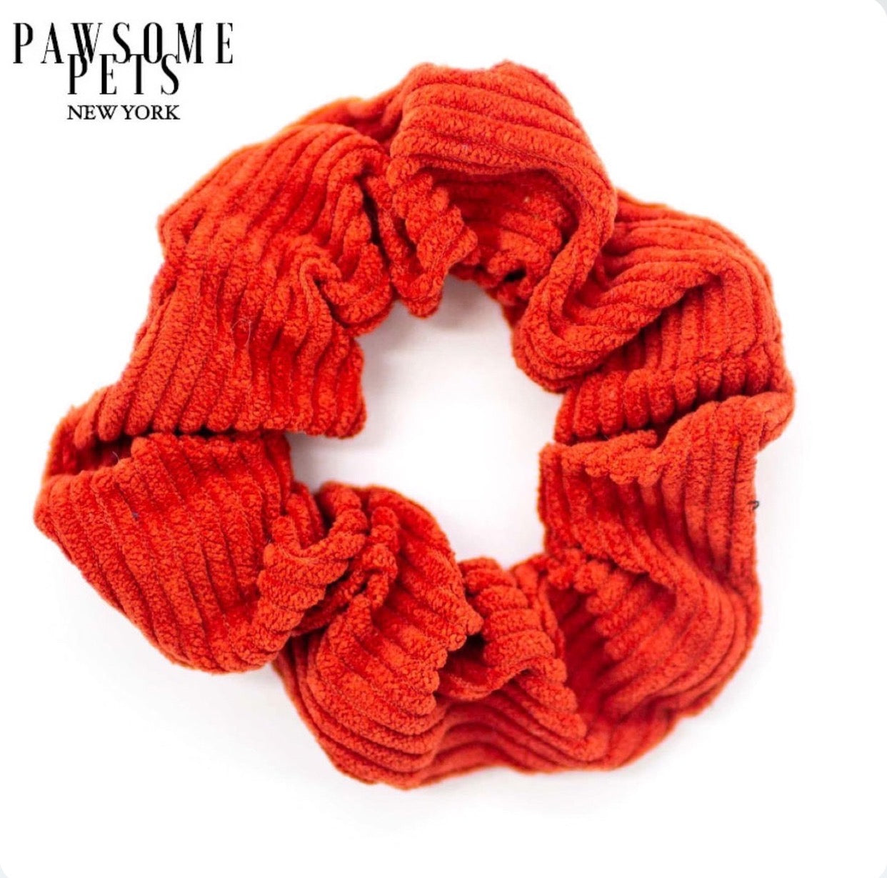A vibrant red scrunchie made from organic cotton, showcasing its soft texture and hand-stitched finish.
