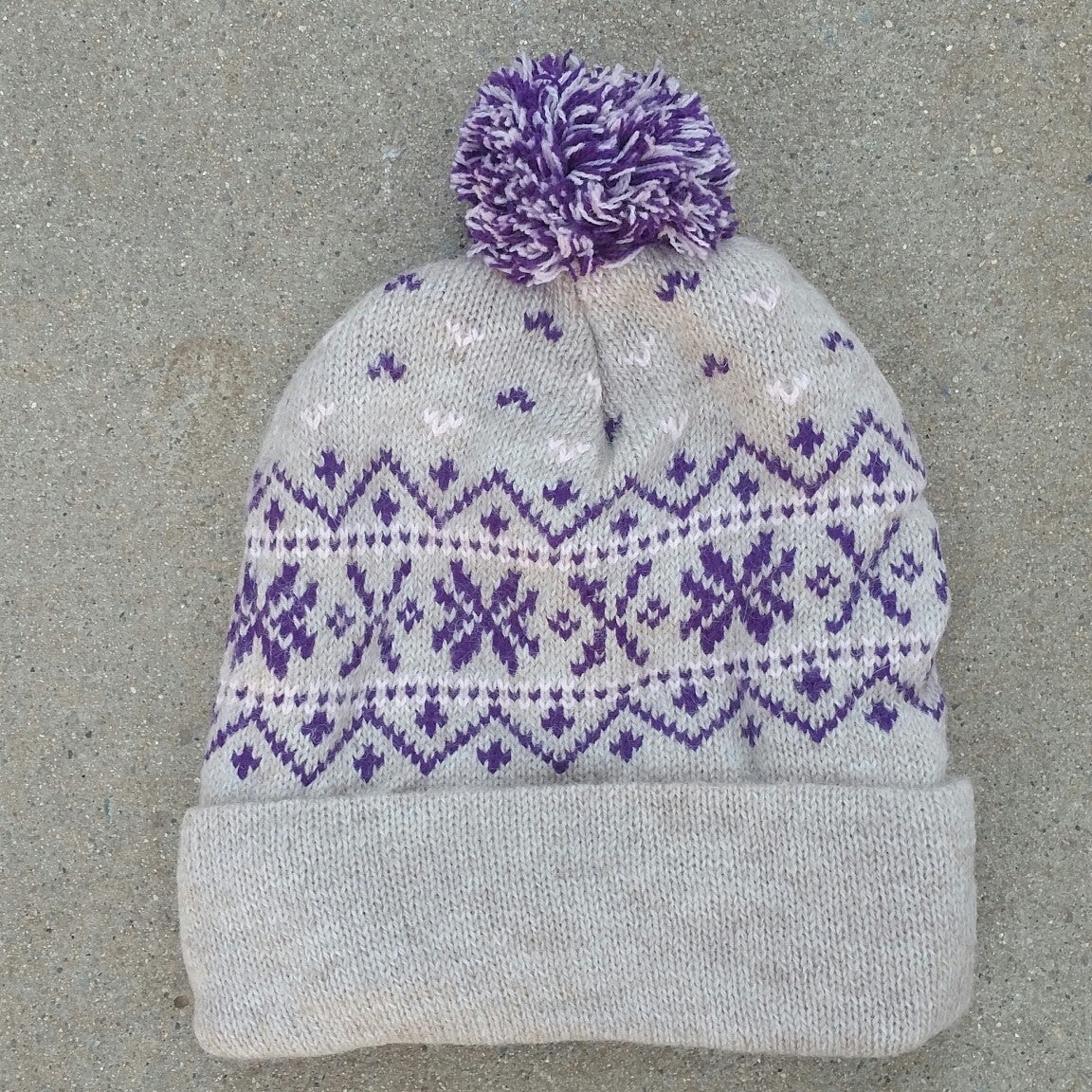 A vibrant Snowflake Pom-Pom Alpaca Hat featuring a snowflake pattern and colorful pom-pom, made from soft SURI Alpaca blend yarn.