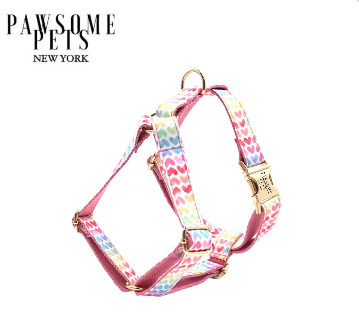 A vibrant pink dog harness featuring a rainbow heart design, made from durable polyester webbing with eco-friendly buckles.