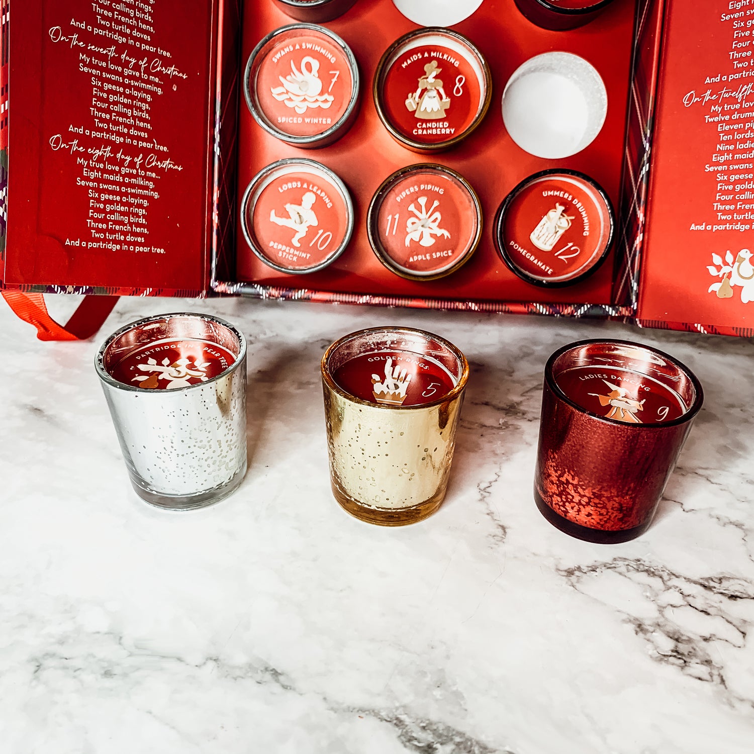 Advent Candle Set featuring 12 scented candles in a festive gift box with Silver, Gold, and Red colors.