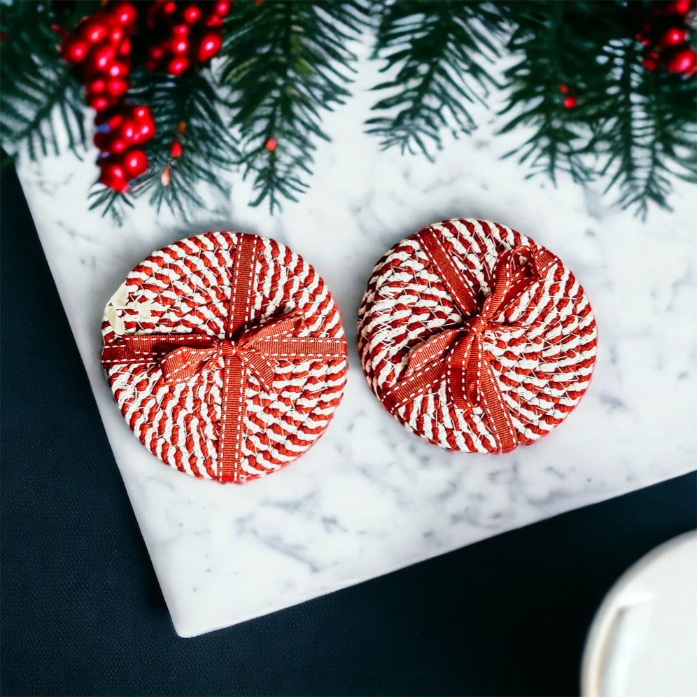 A set of four candy cane striped coasters with braided detail, perfect for holiday decor.