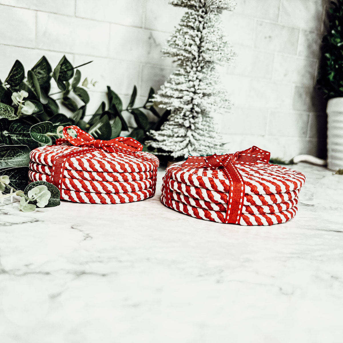 A set of four candy cane striped coasters with braided detail, perfect for holiday decor.