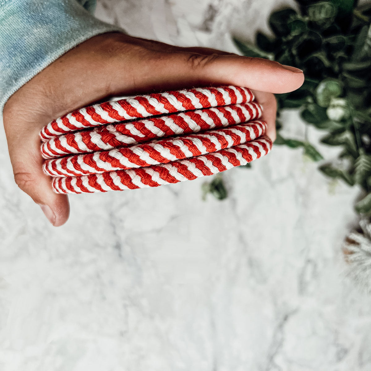 A set of four candy cane striped coasters with braided detail, perfect for holiday decor.