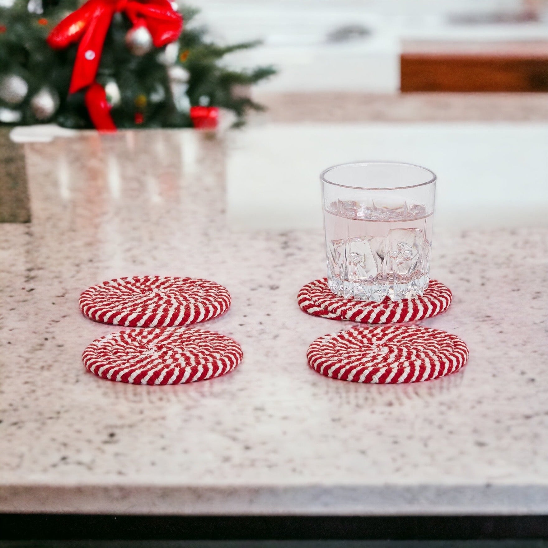 A set of four candy cane striped coasters with braided detail, perfect for holiday decor.
