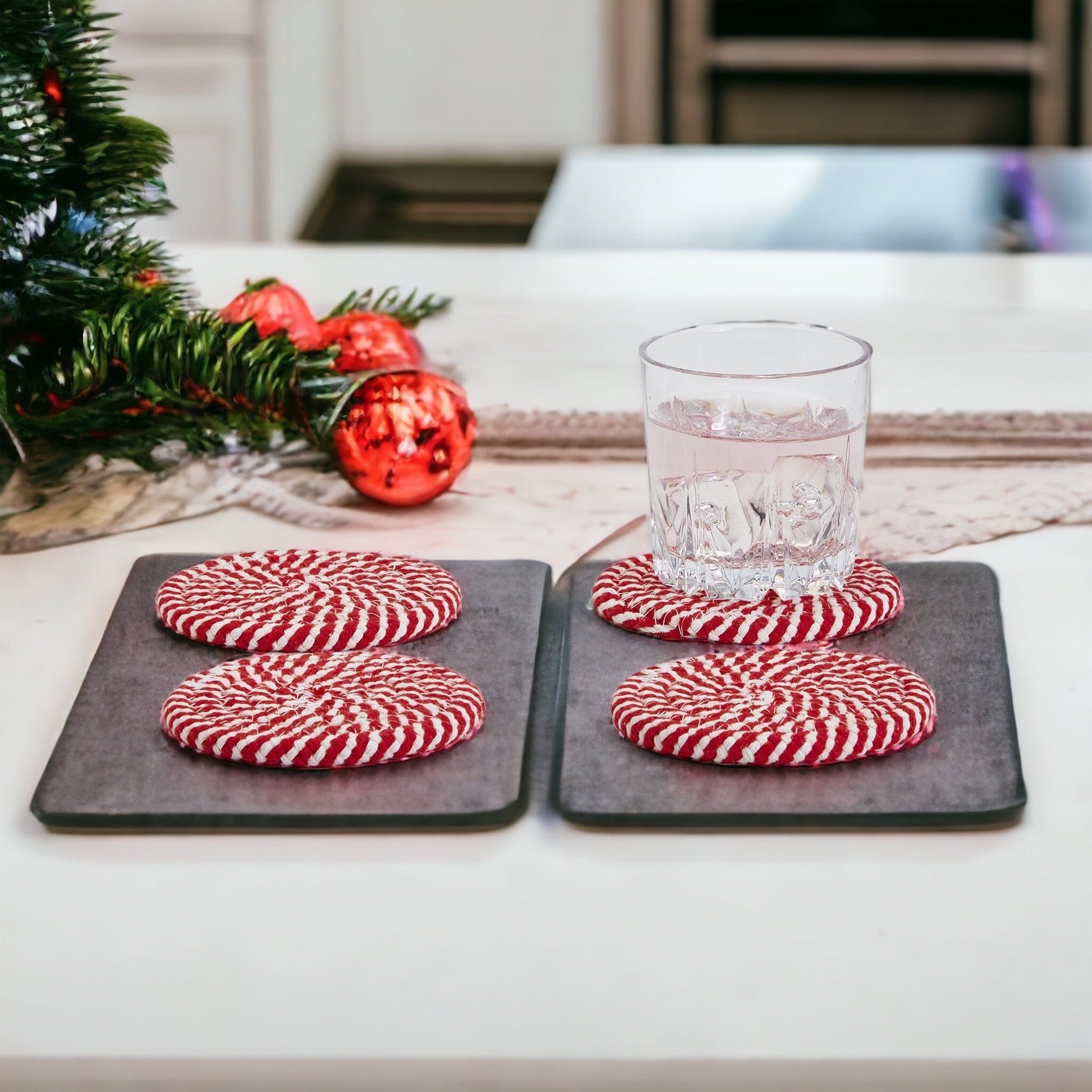 A set of four candy cane striped coasters with braided detail, perfect for holiday decor.