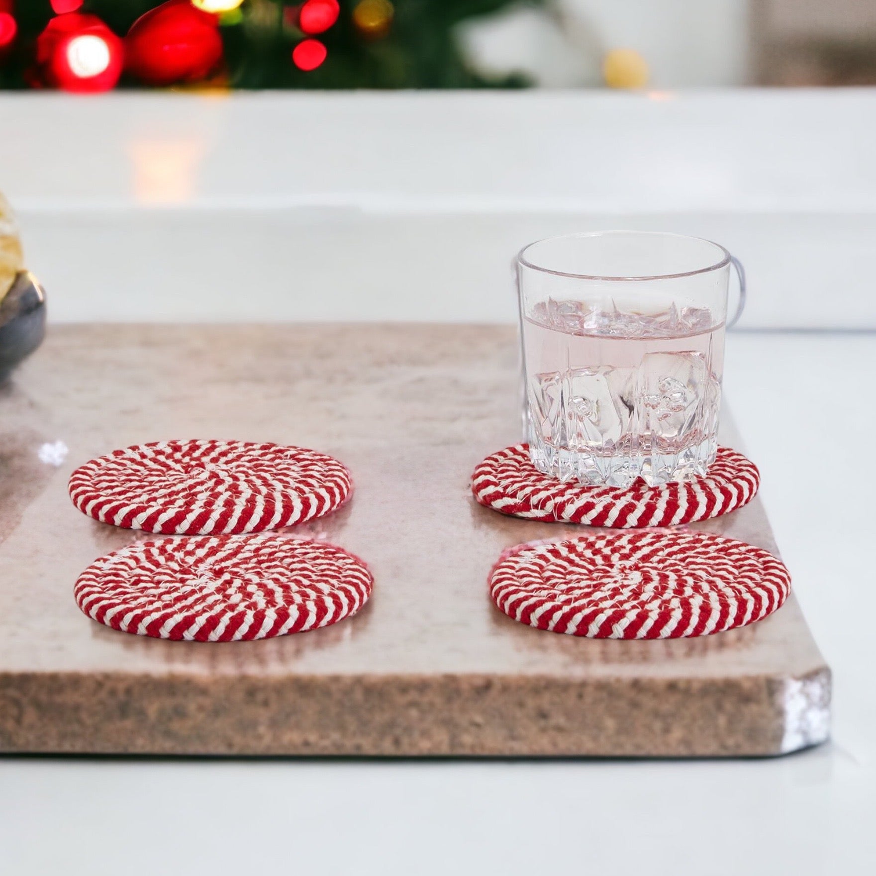 A set of four candy cane striped coasters with braided detail, perfect for holiday decor.