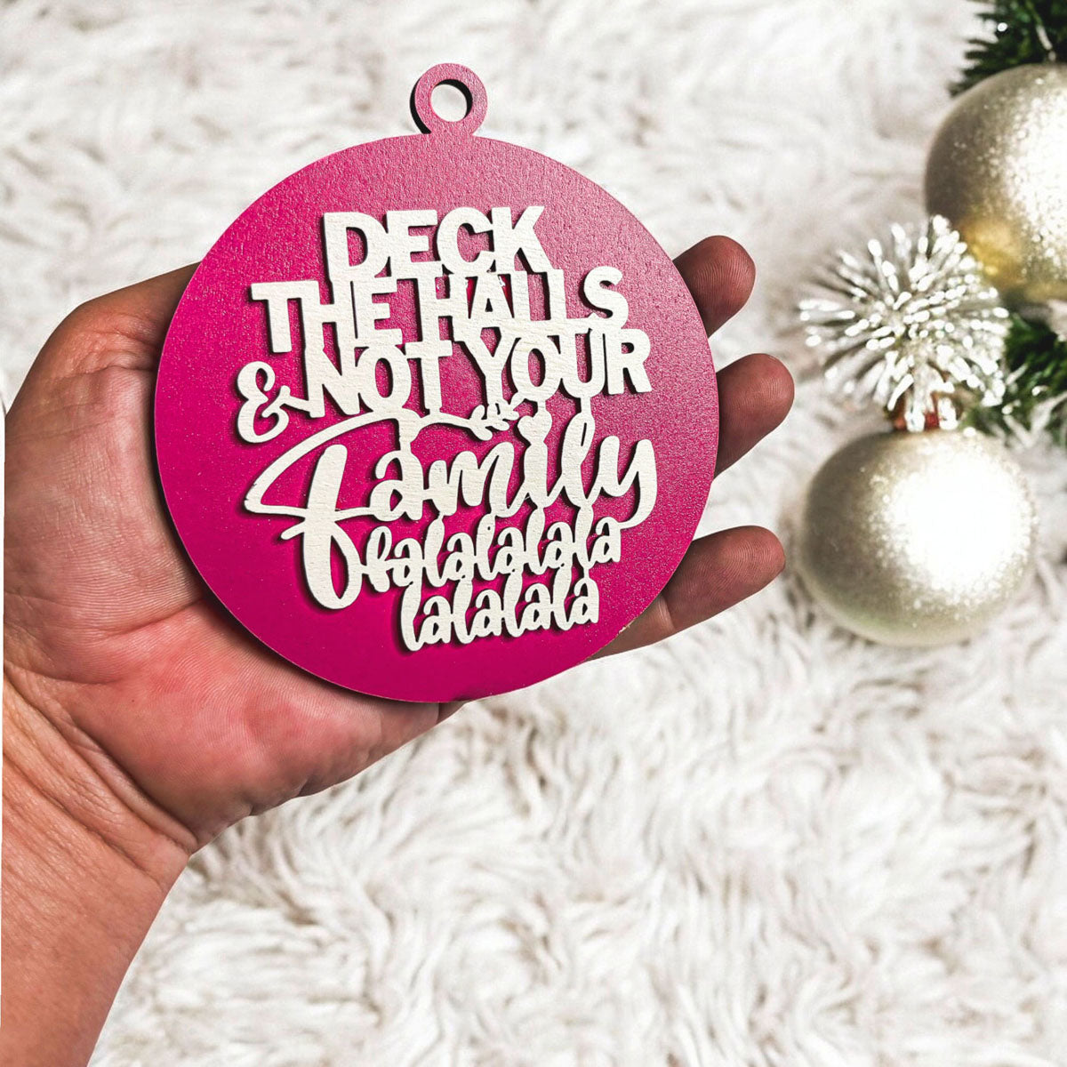 Colorful wooden ornament with the phrase 'Deck the Halls (and Not Your Family)', featuring a 3D design and rustic twine for hanging.