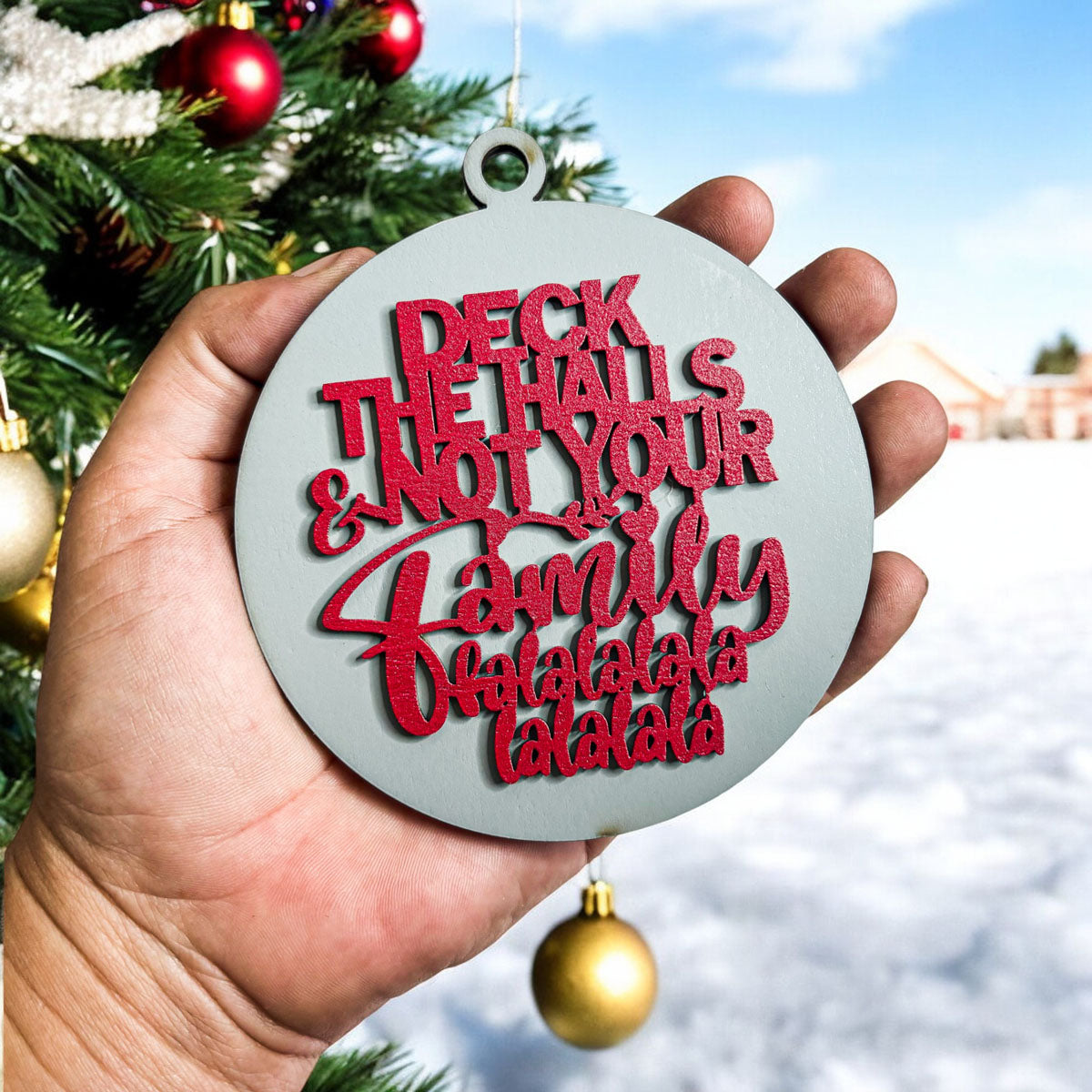 Colorful wooden ornament with the phrase 'Deck the Halls (and Not Your Family)', featuring a 3D design and rustic twine for hanging.