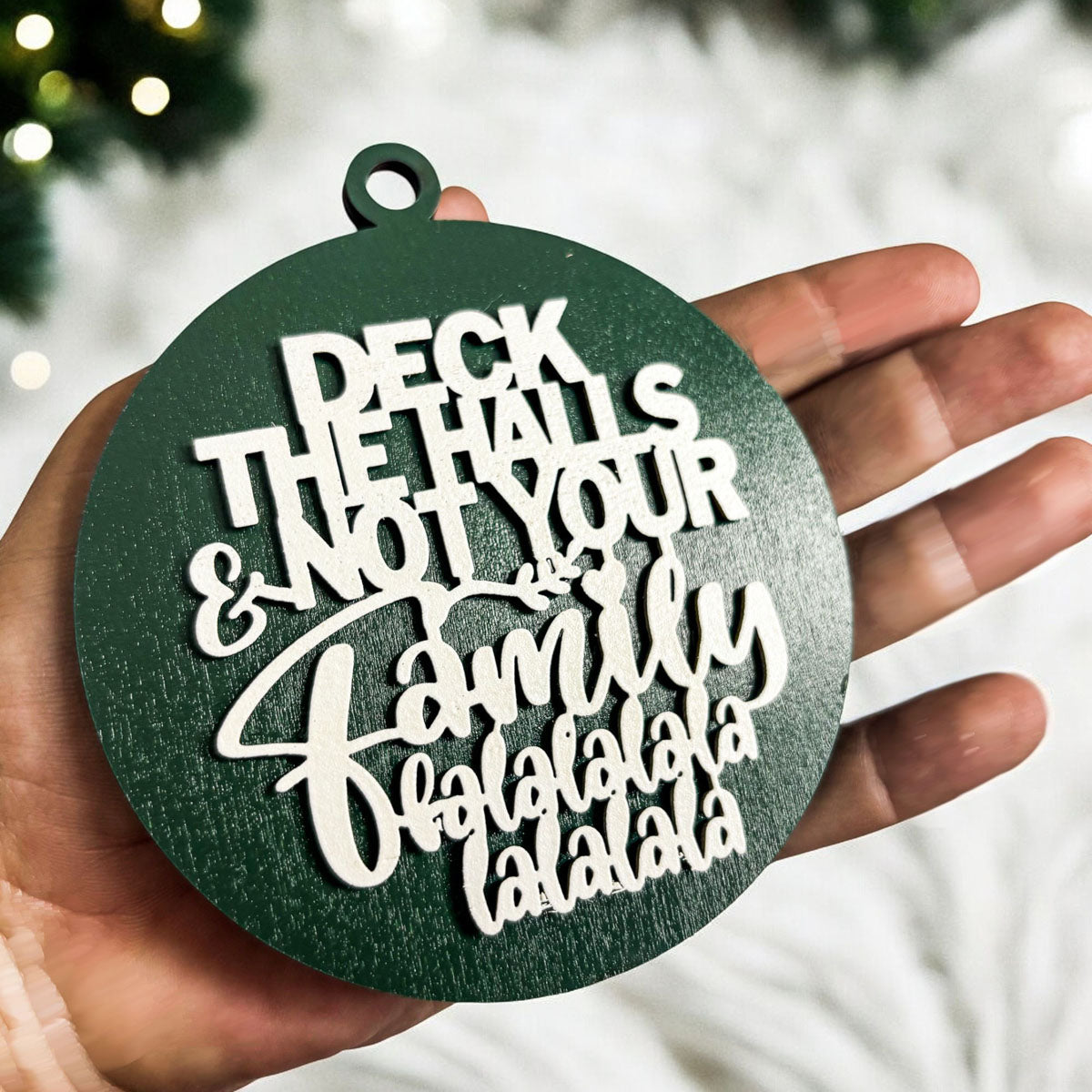 Colorful wooden ornament with the phrase 'Deck the Halls (and Not Your Family)', featuring a 3D design and rustic twine for hanging.