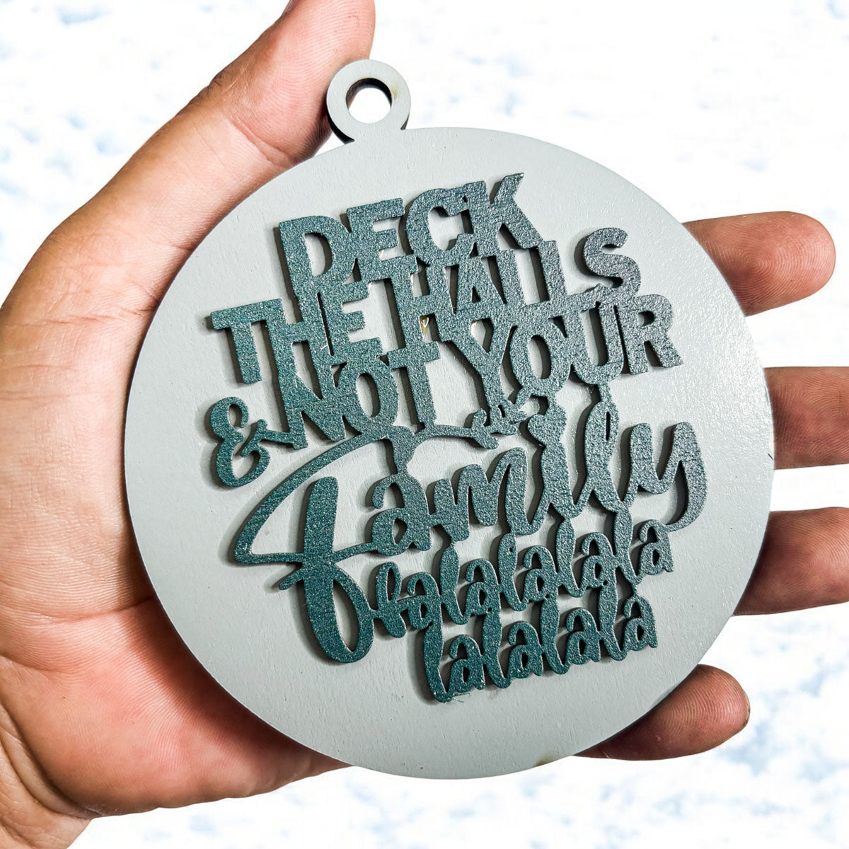 Colorful wooden ornament with the phrase 'Deck the Halls (and Not Your Family)', featuring a 3D design and rustic twine for hanging.