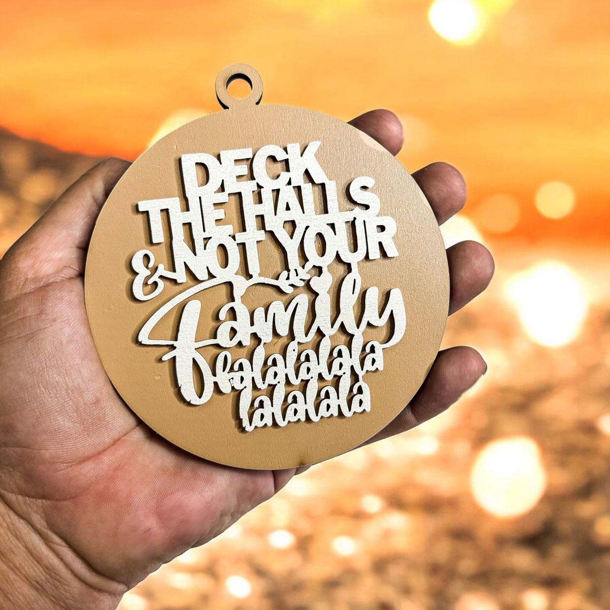 Colorful wooden ornament with the phrase 'Deck the Halls (and Not Your Family)', featuring a 3D design and rustic twine for hanging.