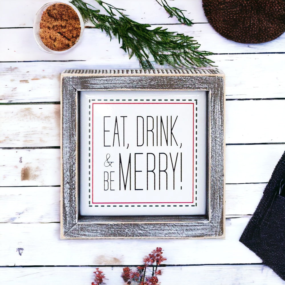 A charming 5-inch wooden framed sign with metal embossed lettering that reads 'Eat, Drink, & Be Merry!' featuring a festive red border.
