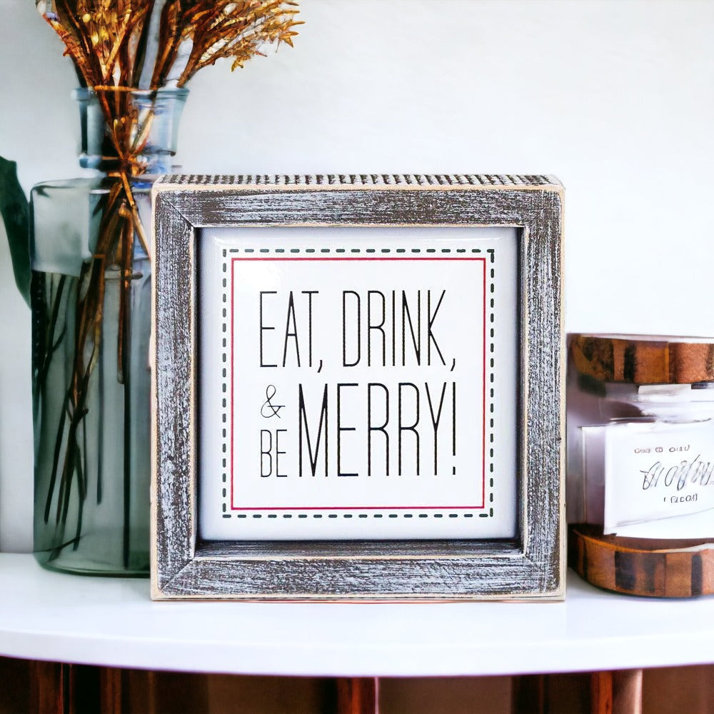 A charming 5-inch wooden framed sign with metal embossed lettering that reads 'Eat, Drink, & Be Merry!' featuring a festive red border.