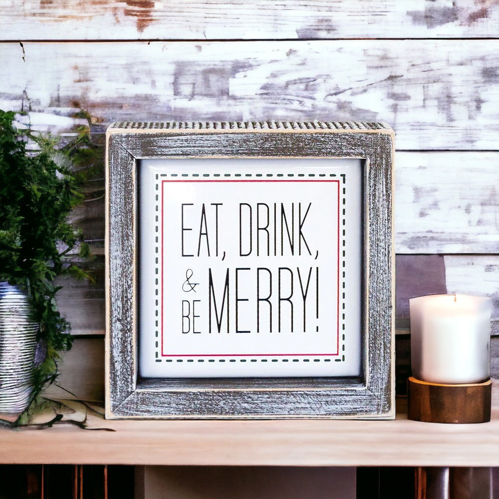 A charming 5-inch wooden framed sign with metal embossed lettering that reads 'Eat, Drink, & Be Merry!' featuring a festive red border.