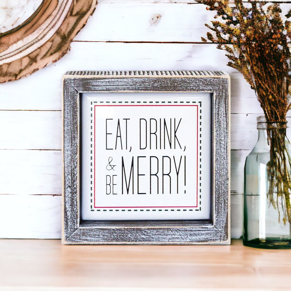A charming 5-inch wooden framed sign with metal embossed lettering that reads 'Eat, Drink, & Be Merry!' featuring a festive red border.