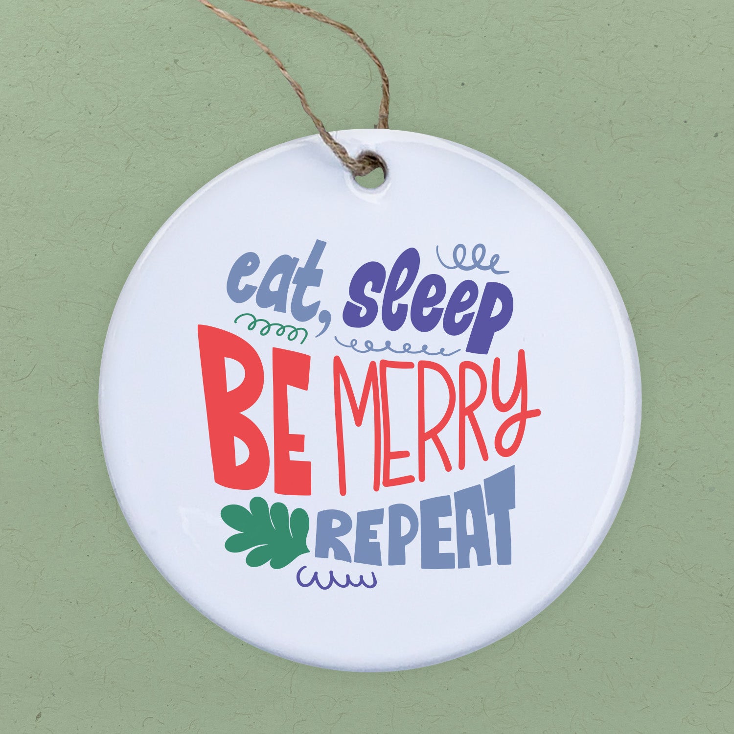 A beautifully crafted porcelain ornament featuring the phrase 'Eat Sleep Be Merry', showcasing vibrant colors and a smooth gloss finish.