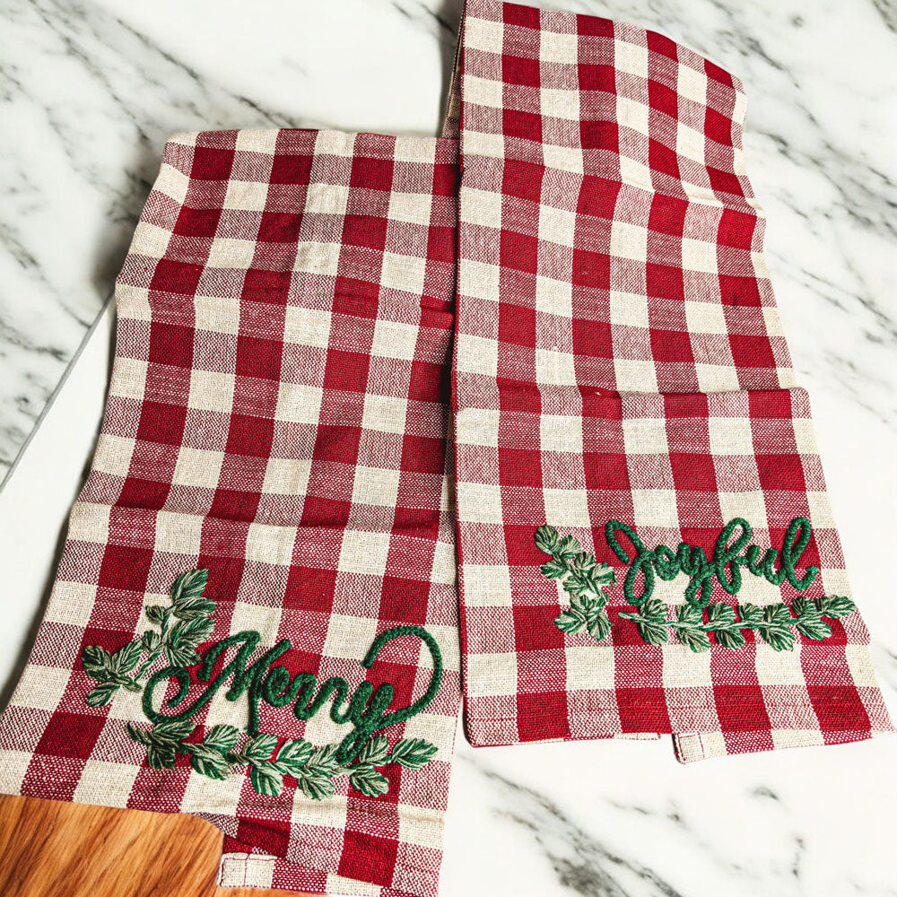 Holiday Charcuterie & Tartan Towel Set featuring a wooden charcuterie board and a tartan print kitchen towel in red and green.