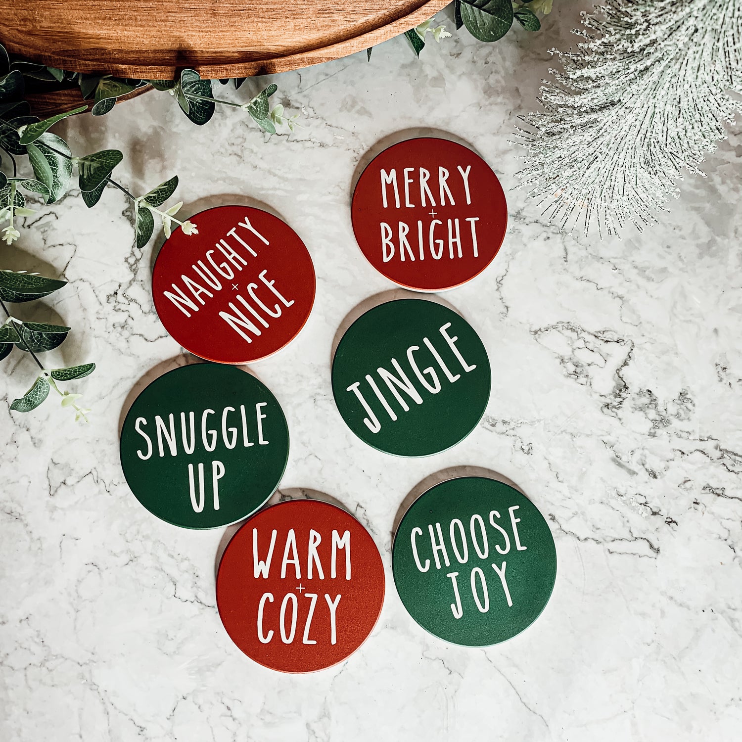 Set of six premium ceramic coasters with cork backing, featuring festive holiday designs including 'Choose Joy' and 'Merry + Bright'.