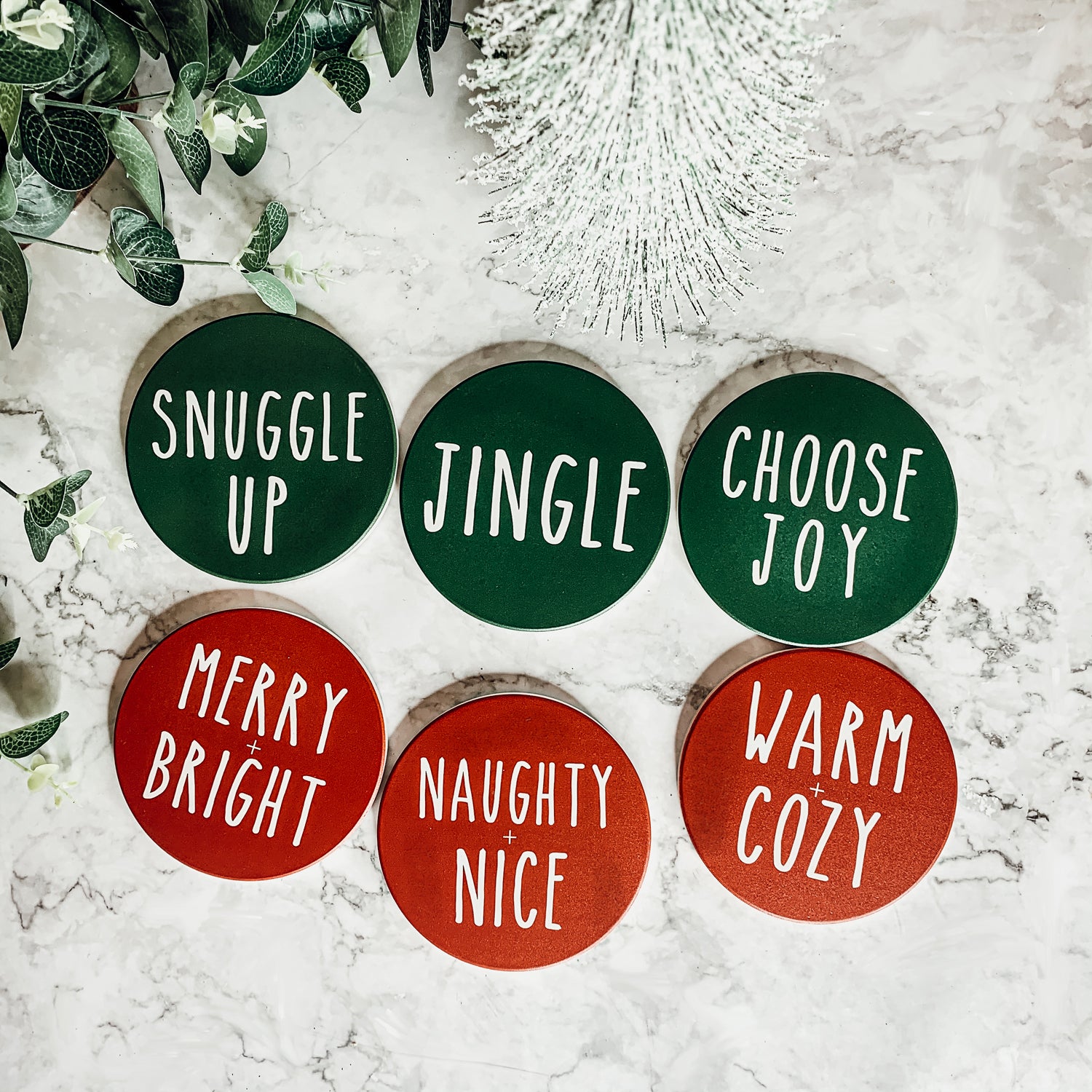 Set of six premium ceramic coasters with cork backing, featuring festive holiday designs including 'Choose Joy' and 'Merry + Bright'.