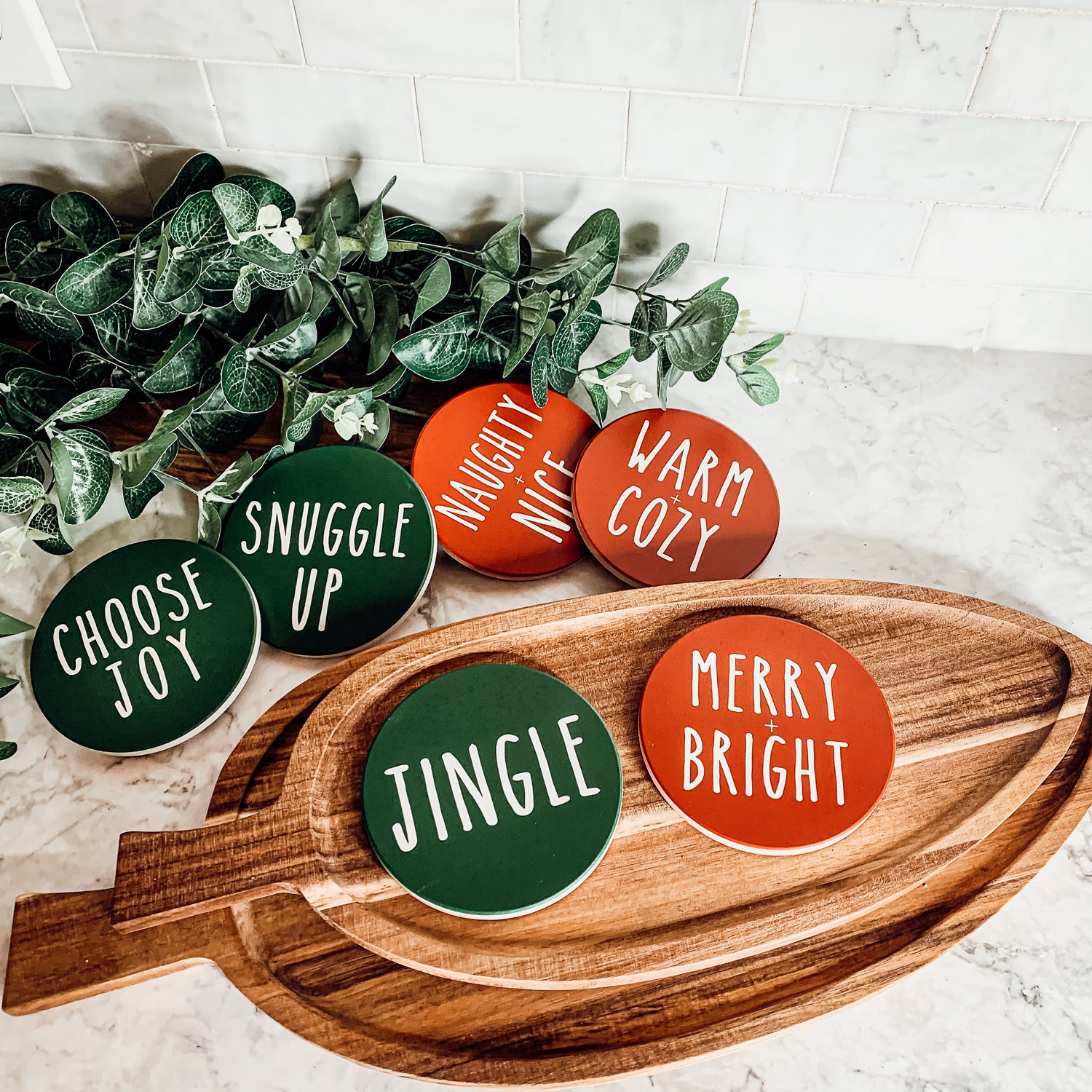 Set of six premium ceramic coasters with cork backing, featuring festive holiday designs including 'Choose Joy' and 'Merry + Bright'.