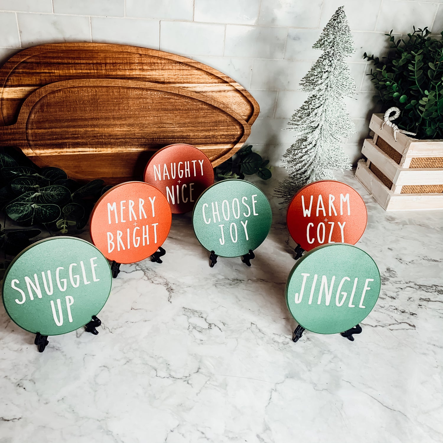 Set of six premium ceramic coasters with cork backing, featuring festive holiday designs including 'Choose Joy' and 'Merry + Bright'.