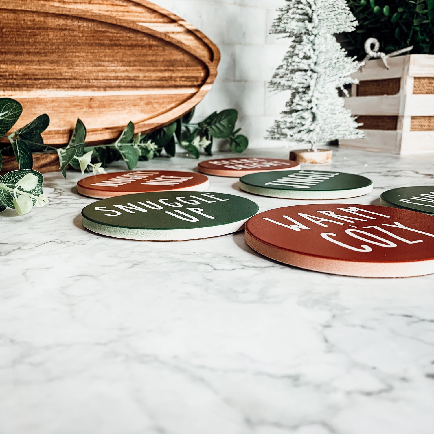 Set of six premium ceramic coasters with cork backing, featuring festive holiday designs including 'Choose Joy' and 'Merry + Bright'.