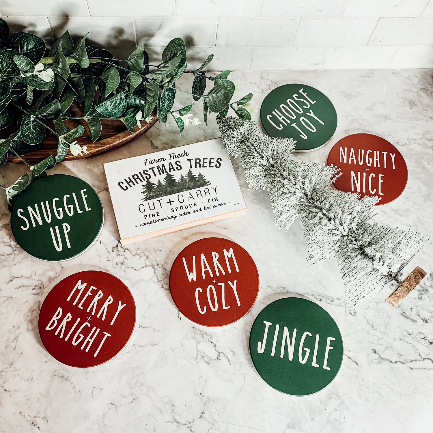 Set of six premium ceramic coasters with cork backing, featuring festive holiday designs including 'Choose Joy' and 'Merry + Bright'.