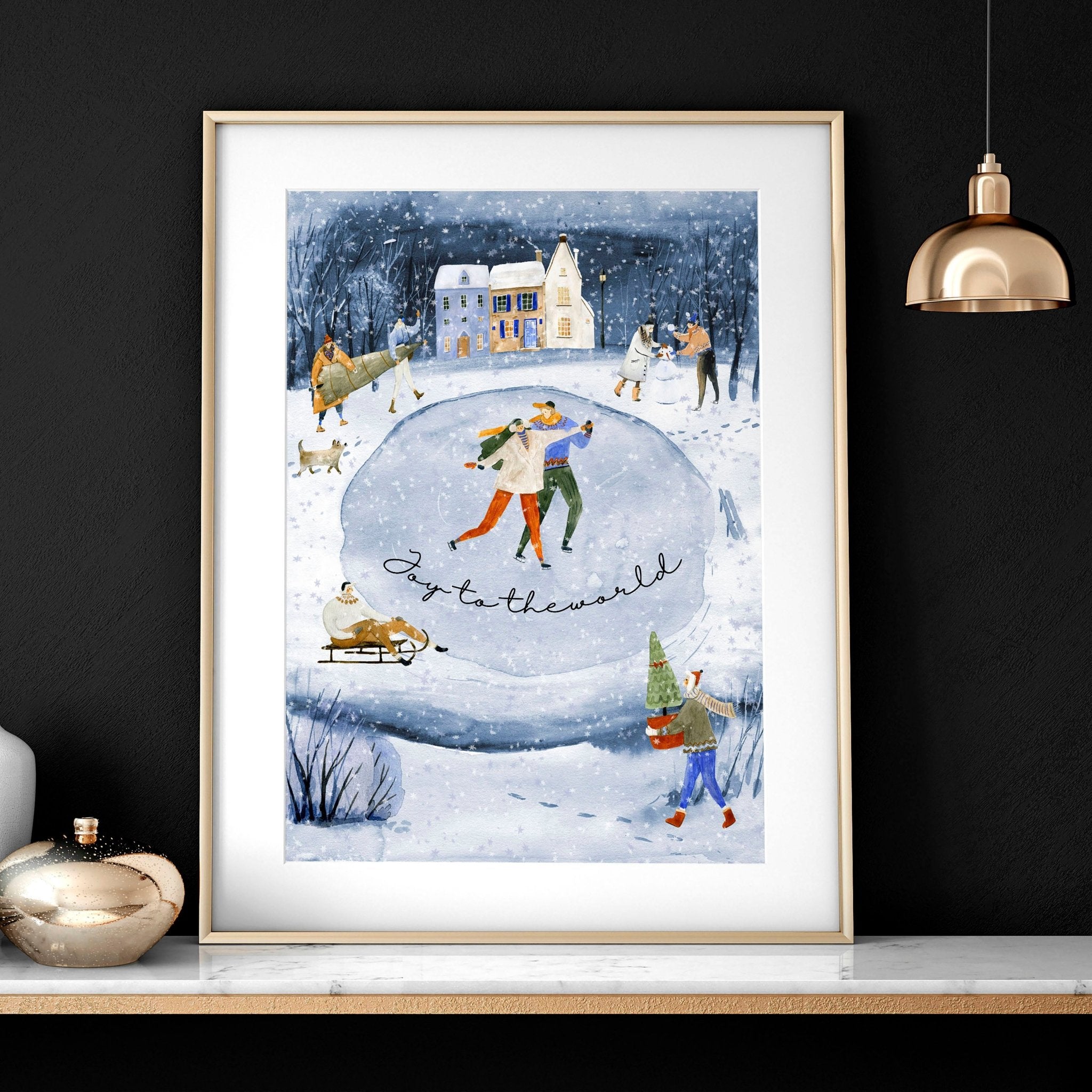 A beautiful indoor Christmas wall art print featuring a serene blue watercolour landscape with a snowy pond and a charming village adorned with lights.