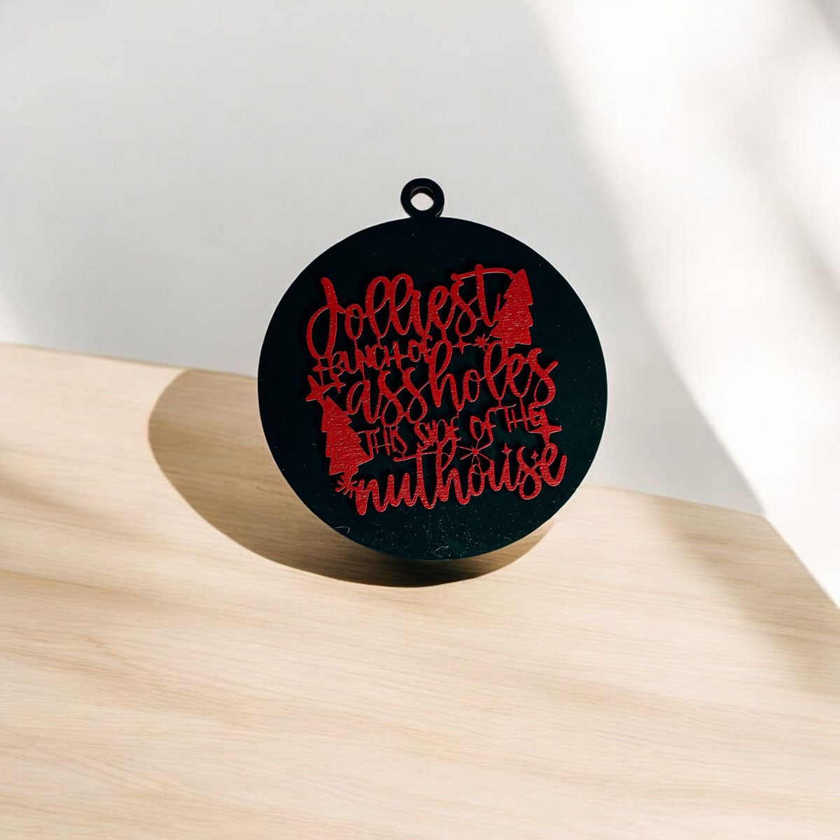 Jolliest Bunch Wooden Ornament featuring festive graphics and rustic twine, available in 12 vibrant colors.
