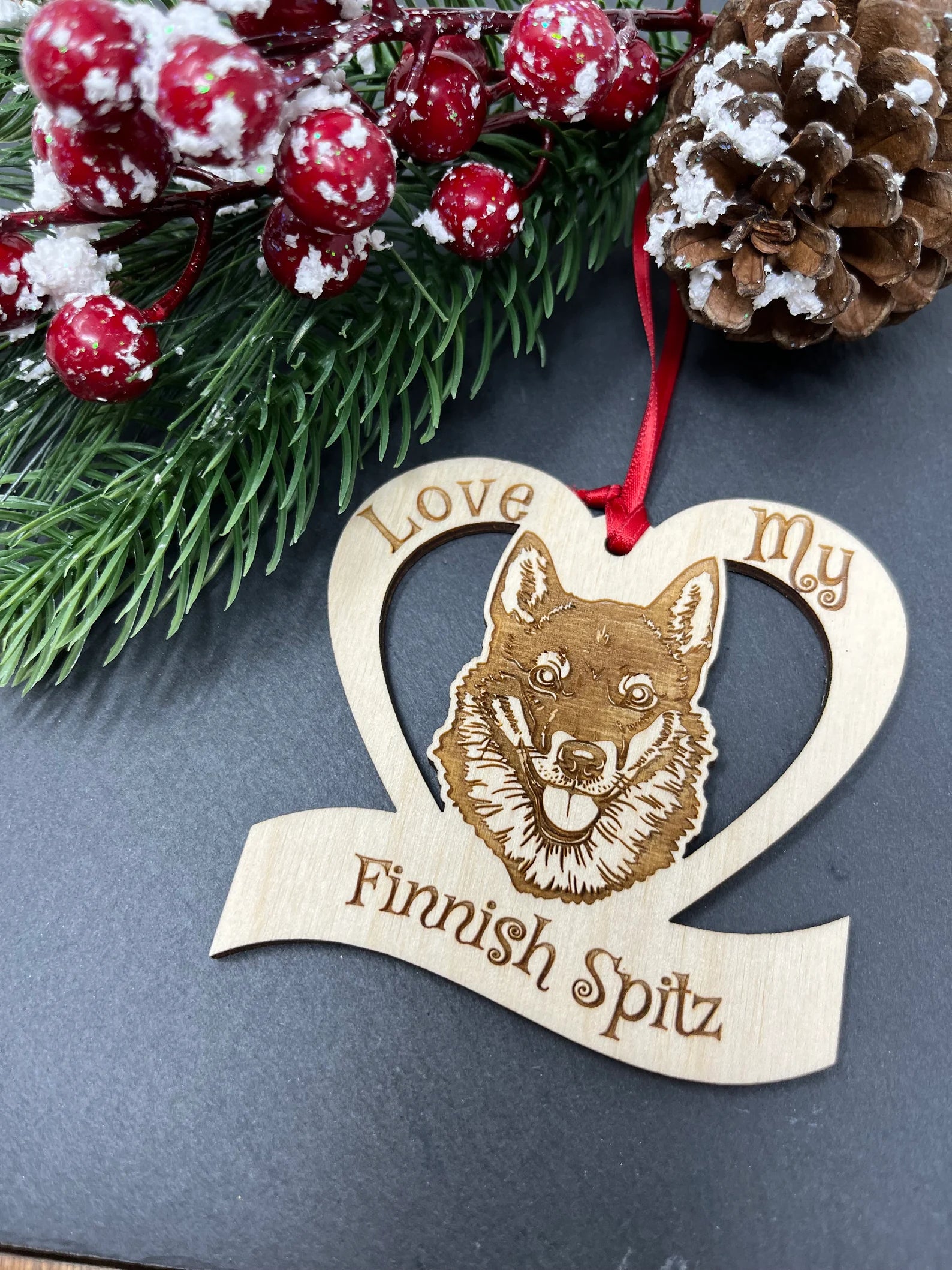 A beautifully crafted Love My Finnish Spitz ornament made from laser engraved Baltic Birch wood, featuring a unique design and attached ribbon for hanging.