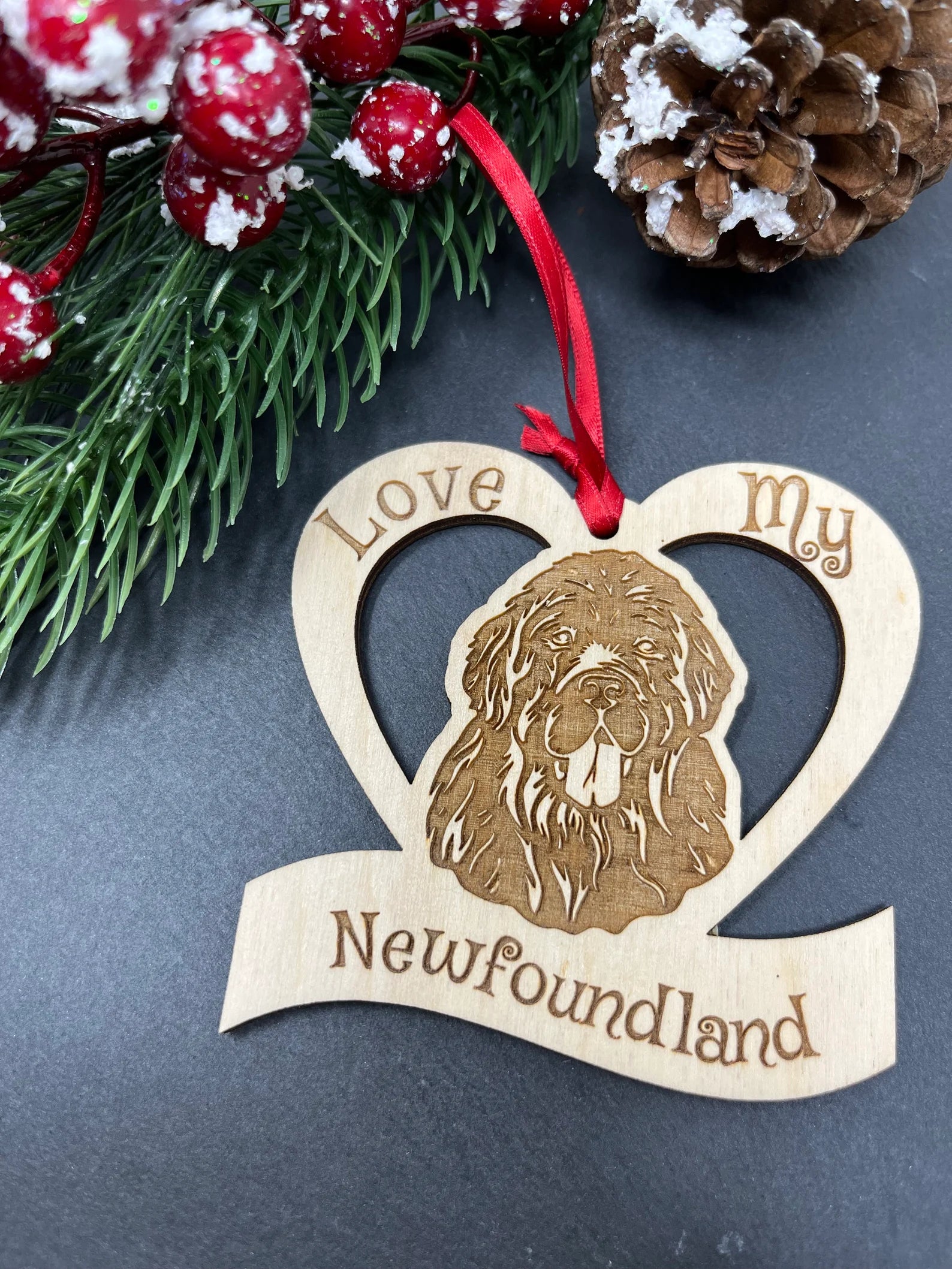 Love My Newfoundland ornament made of laser engraved Baltic Birch wood, featuring a unique design and attached ribbon for hanging.