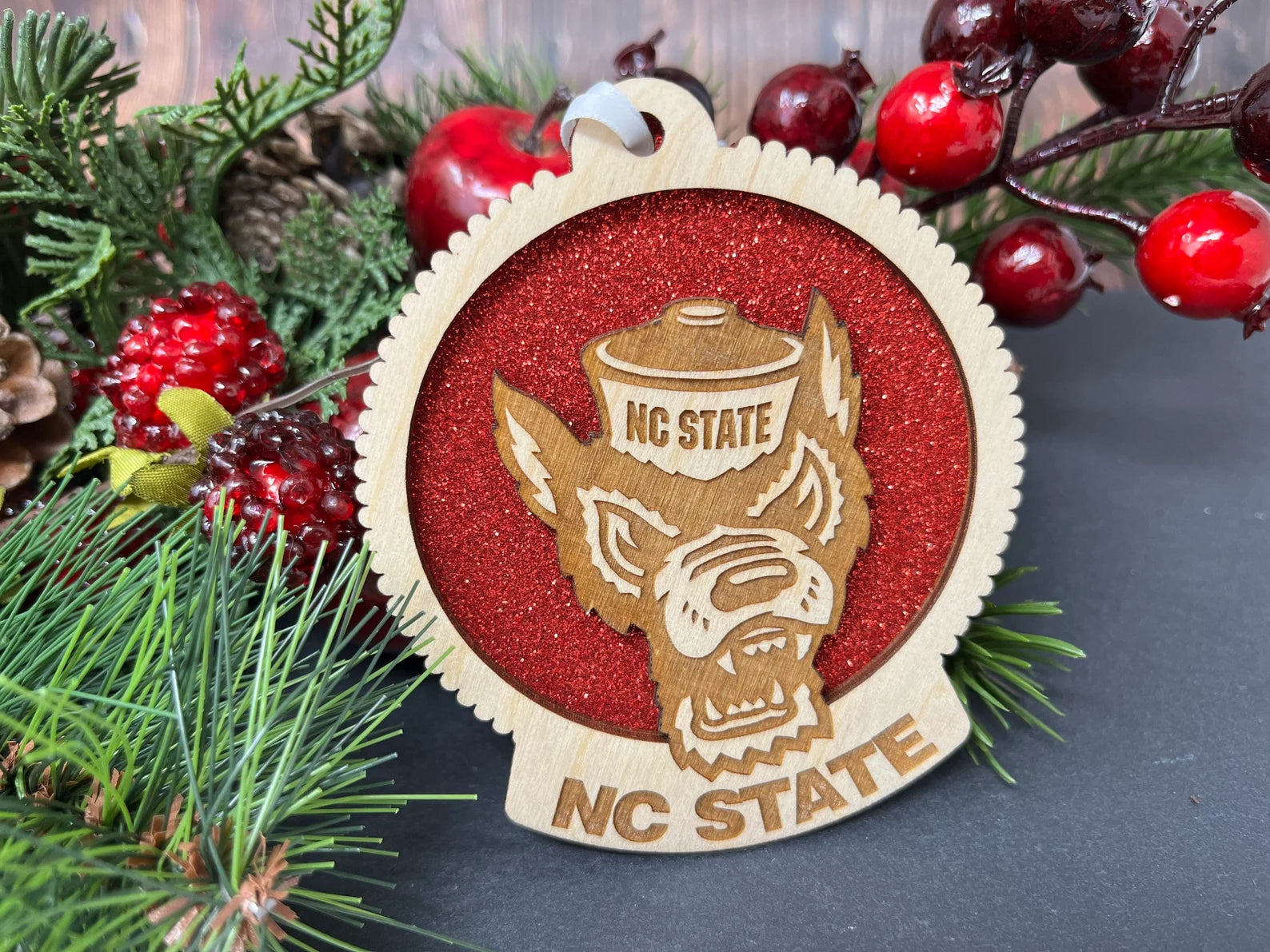 Handcrafted North Carolina State University ornament made of birch wood, featuring the Wolf Pack logo, measuring 4x4 inches, packaged in a premium box.