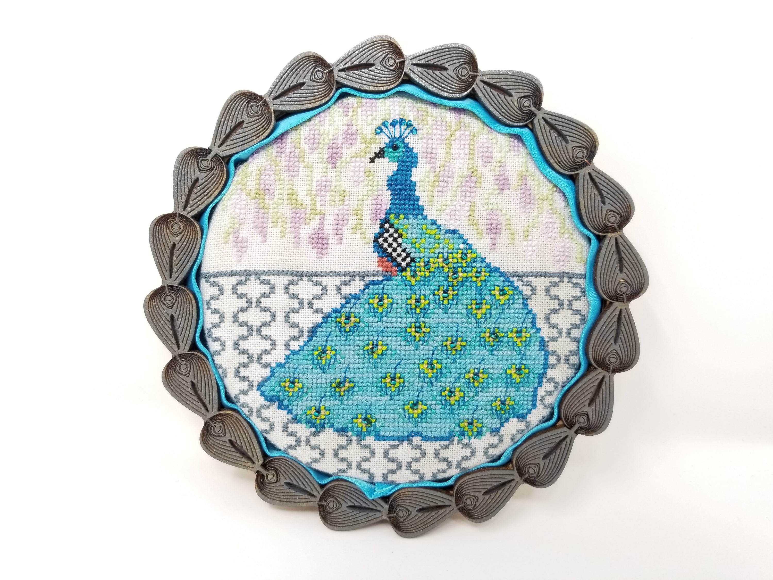Peacock Prince cross-stitch pattern designed by Suzzanne Brakefield, featuring vibrant colors and intricate details.