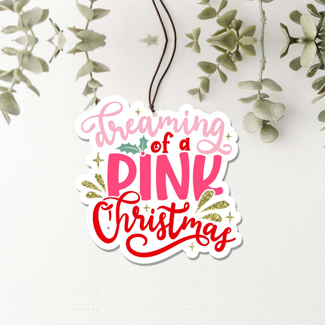 A pink Christmas air freshener shaped like a festive ornament, hanging with a decorative design, perfect for holiday decor.