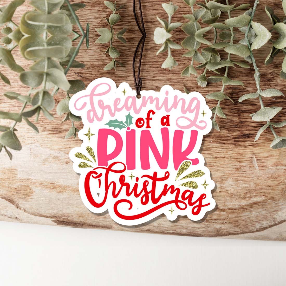 A pink Christmas air freshener shaped like a festive ornament, hanging with a decorative design, perfect for holiday decor.