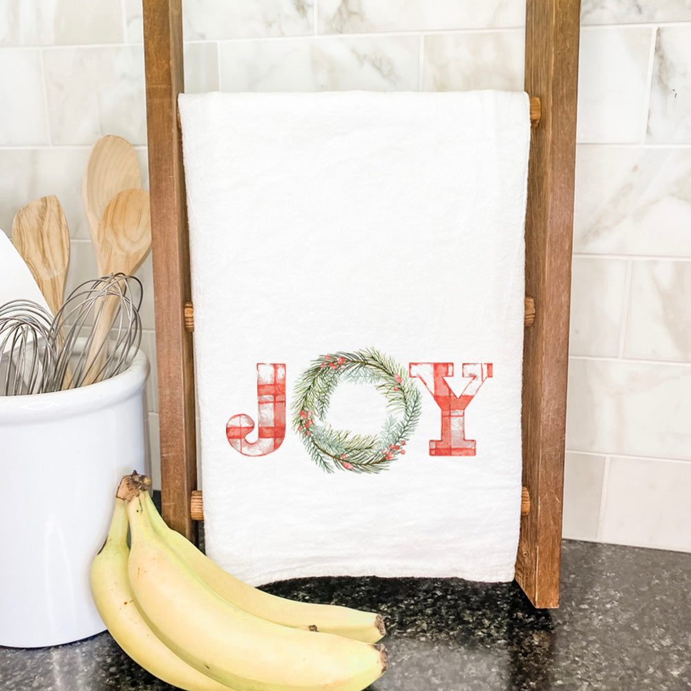 Plaid Joy Wreath Cotton Tea Towel featuring a vibrant plaid design, hemmed edges, and a soft texture, ideal for kitchen use.