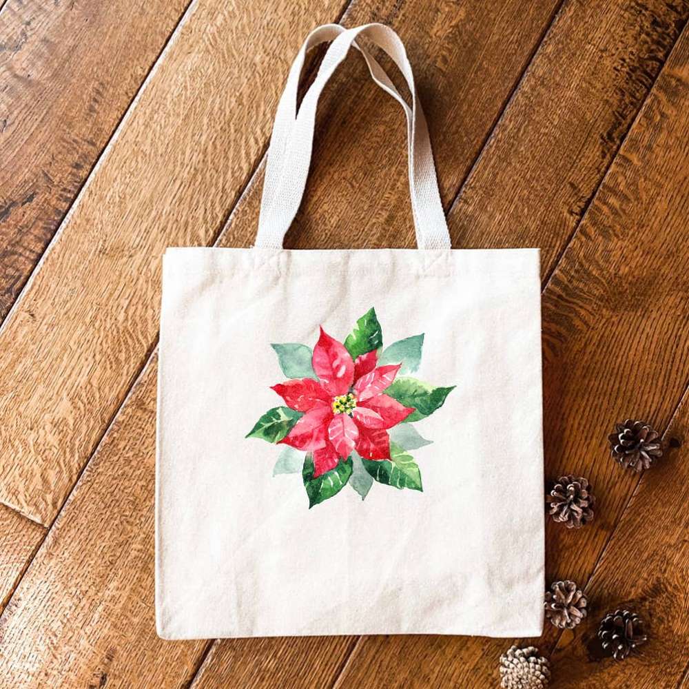 A vibrant Poinsettia Canvas Tote Bag featuring a beautiful floral design, made from heavy-duty canvas with reinforced webbing straps.