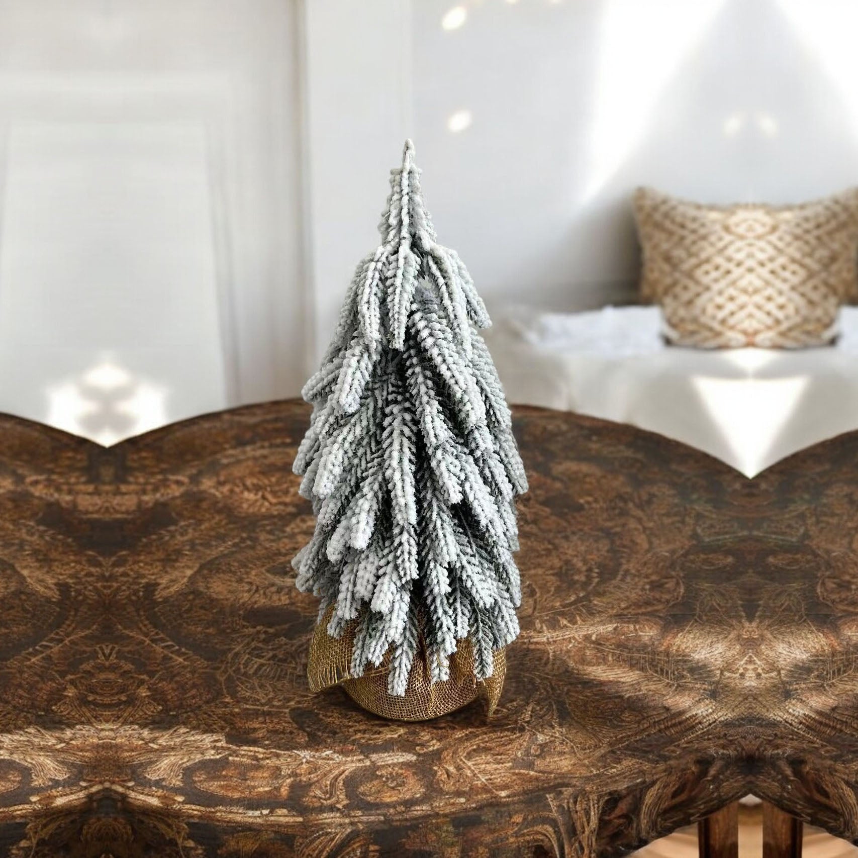 A set of four snow-covered Christmas trees in varying sizes, featuring a jute-covered wooden base, perfect for holiday decor.