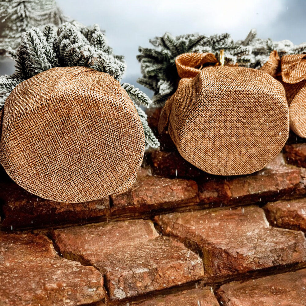 A set of four snow-covered Christmas trees in varying sizes, featuring a jute-covered wooden base, perfect for holiday decor.