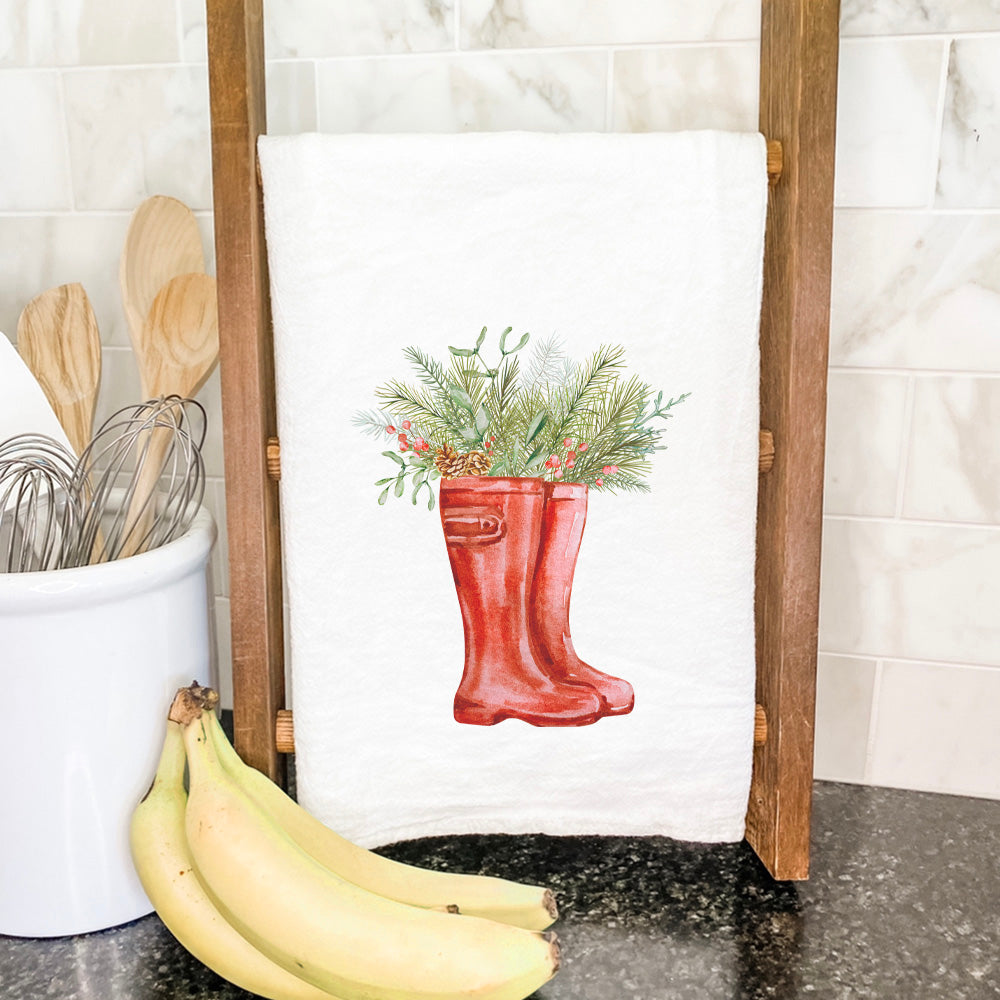 A beautifully designed cotton tea towel featuring winter rain boots and foliage, showcasing vibrant colors and intricate details.