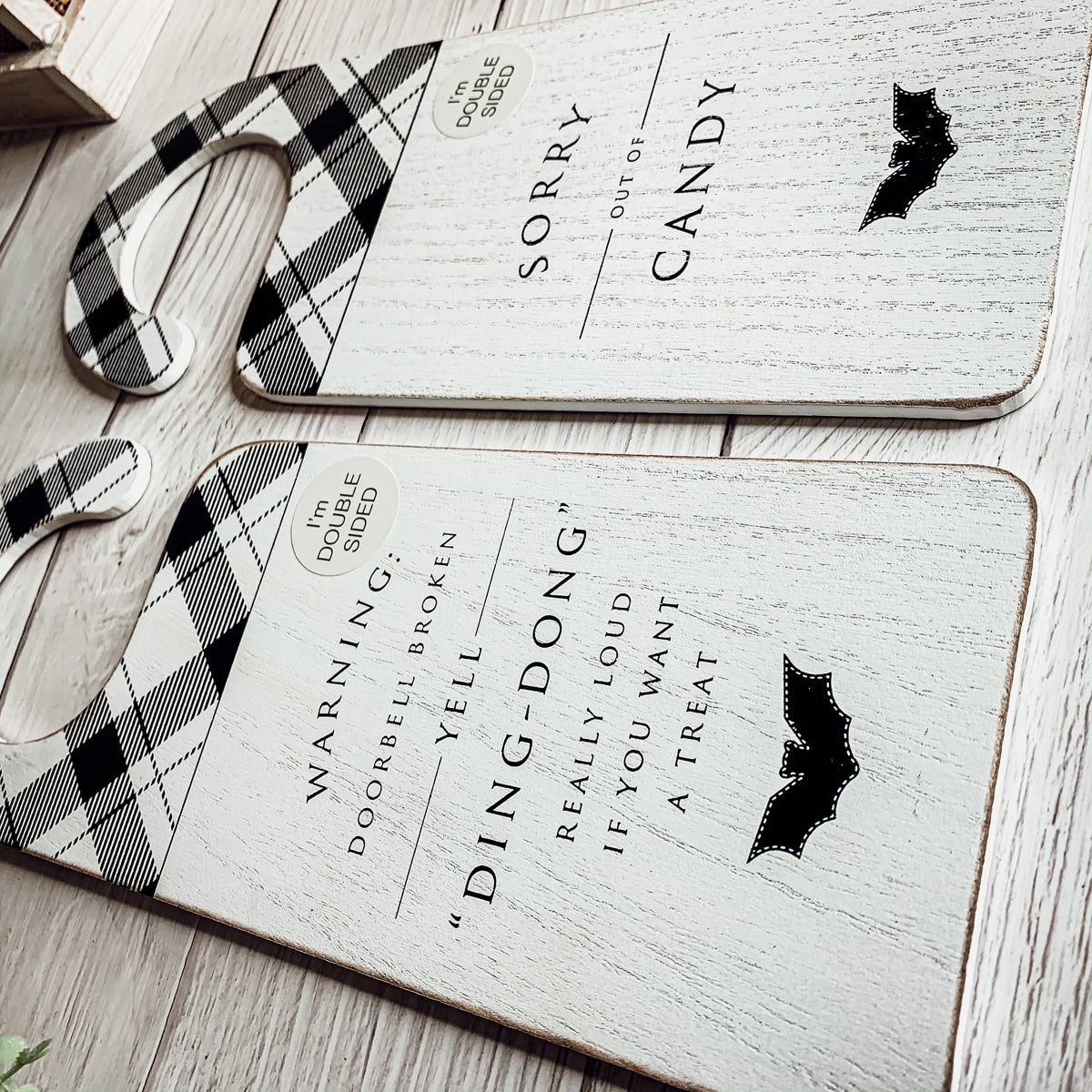 A double-sided Halloween door knob sign featuring 'Ding Dong' on one side and a spooky design on the other, perfect for festive decor.