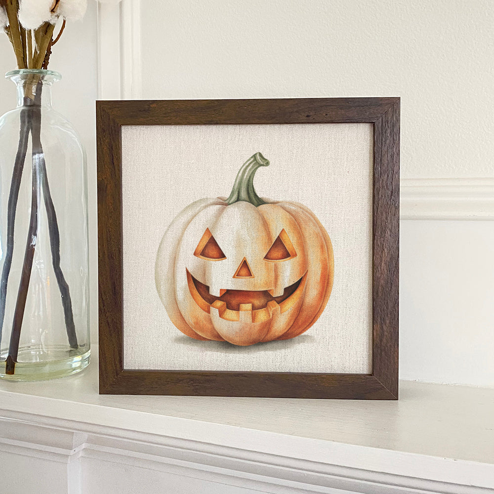 A beautifully framed sign featuring a watercolor carved pumpkin design, set against a linen-look neutral background with a stylish wood frame.