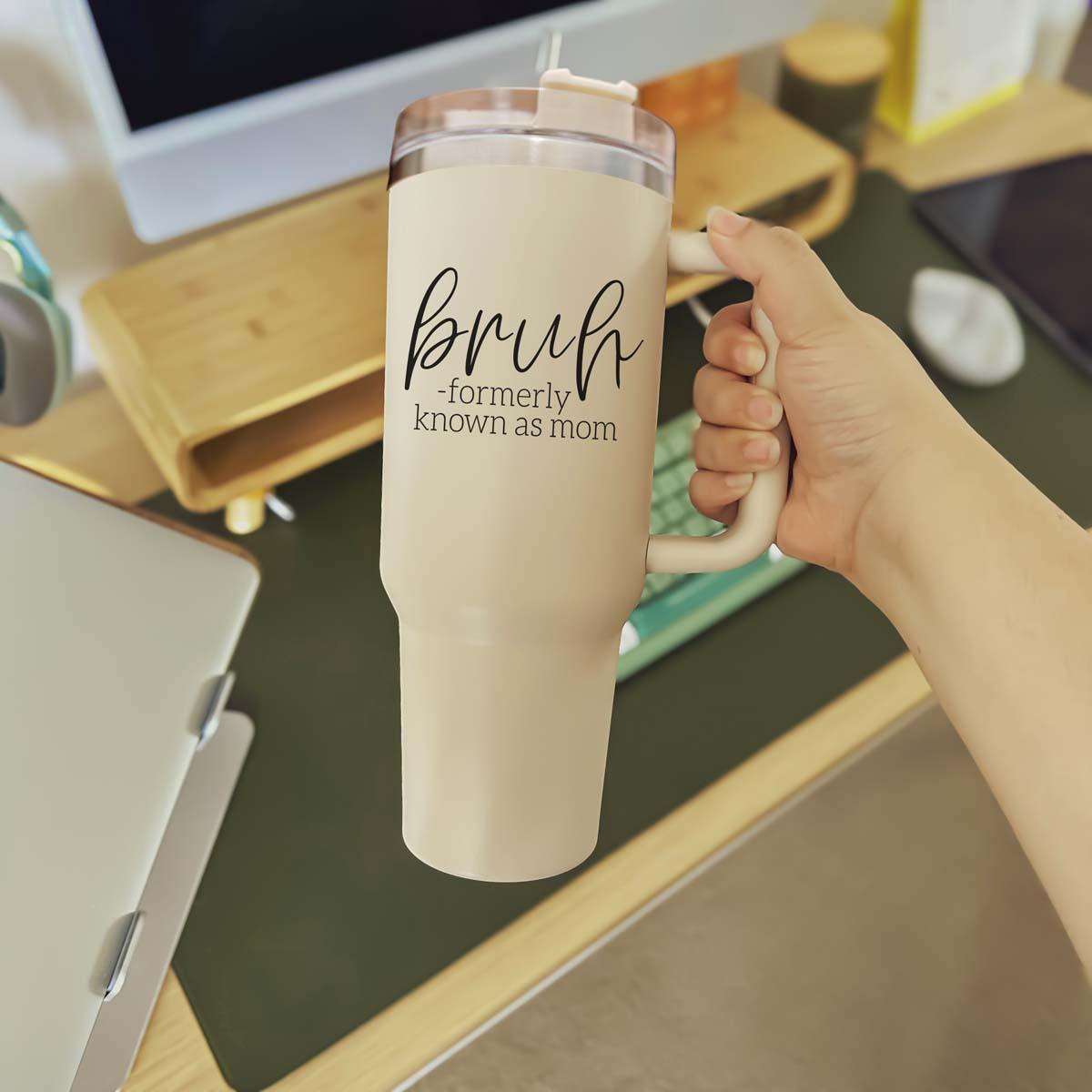 Bruh 40oz tumbler with cream exterior and black graphic design, featuring a handle and a versatile 3-in-1 lid.