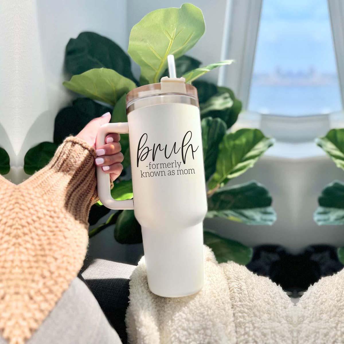 Bruh 40oz tumbler with cream exterior and black graphic design, featuring a handle and a versatile 3-in-1 lid.