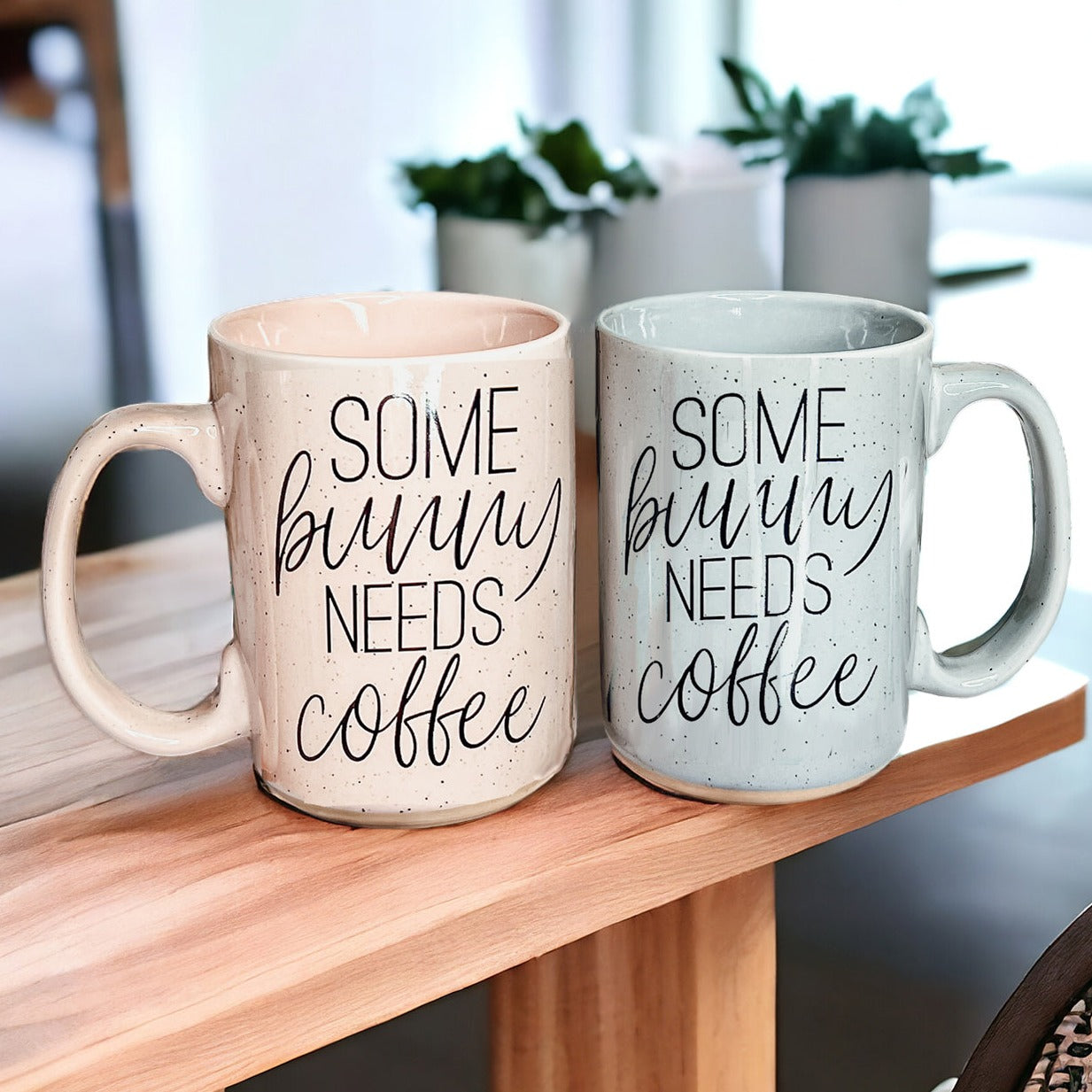 Ceramic coffee mug with pastel blue and pink colors, featuring the phrase 'Some Bunny Needs Coffee' on both sides, perfect for Easter and spring.
