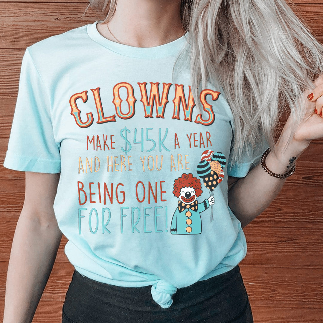 A humorous t-shirt featuring the phrase 'Clowns Make 45K A Year And Here You Are Being One For Free' printed on soft cotton fabric.