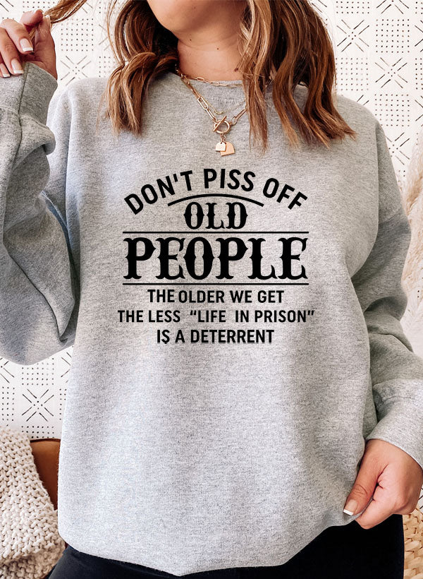 A cozy sweatshirt featuring the phrase 'Don't Piss Off Old People' in bold letters, made from a soft cotton/poly fleece blend.
