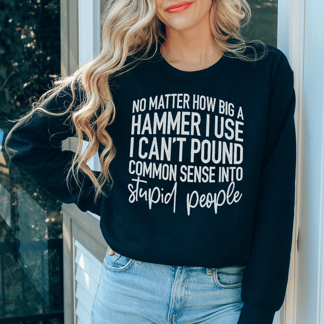A cozy sweatshirt featuring the phrase 'I Can't Pound Common Sense Into Stupid People', designed by top artists, showcasing a unique and humorous style.