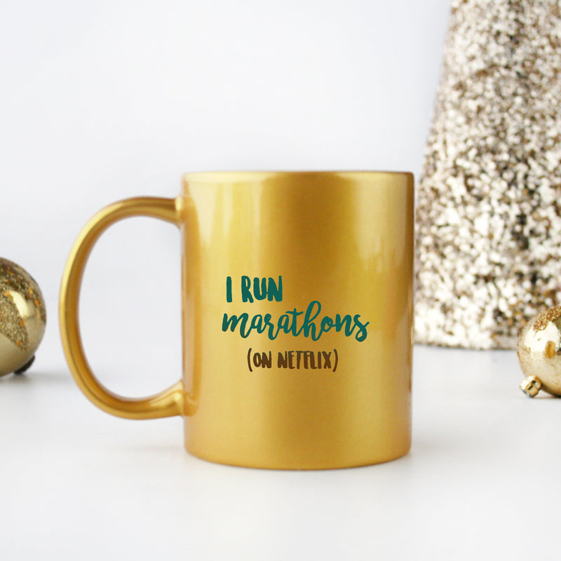 Ceramic gold and silver mug with 'I Run Marathons On Netflix' design, perfect for coffee lovers and binge-watchers.